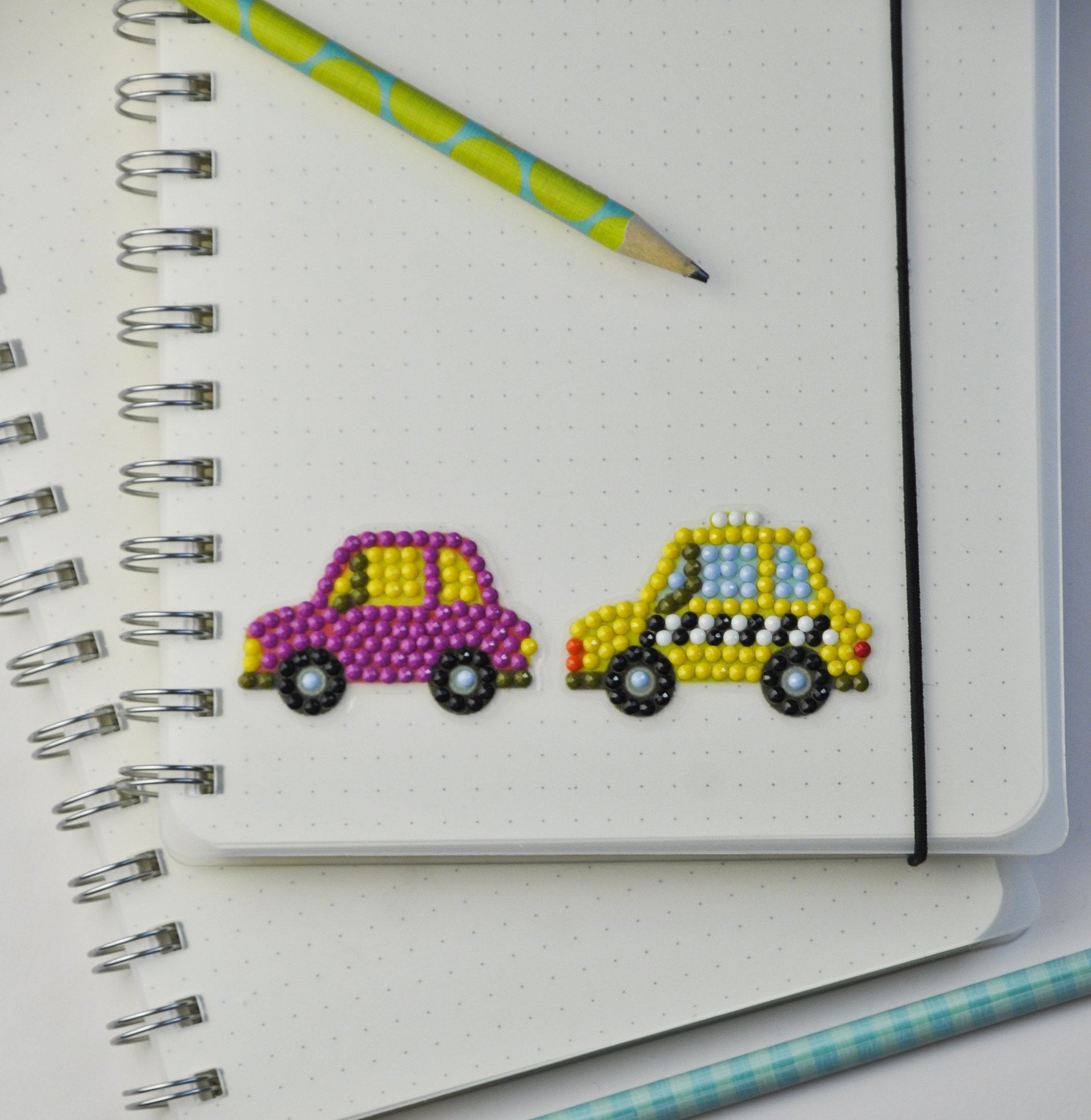 Fertiger Diamond Painting Sticker mit pinkem Auto und gelbem Taxi als persönliche Dekoration auf einem Notizbuch