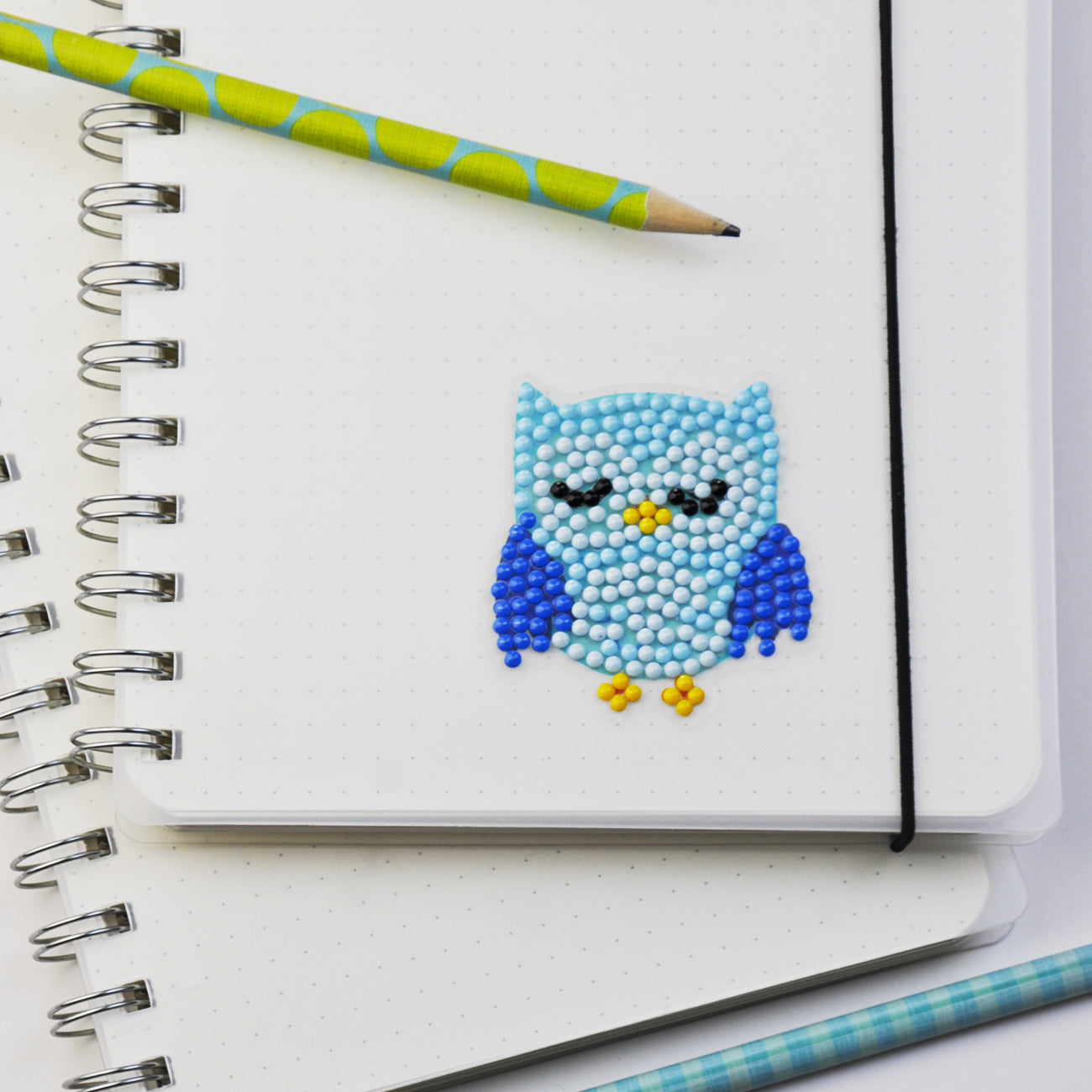 Fertiger Diamond Painting Sticker mit blauem Eulenmotiv als persönliche Dekoration auf einem Notizbuch