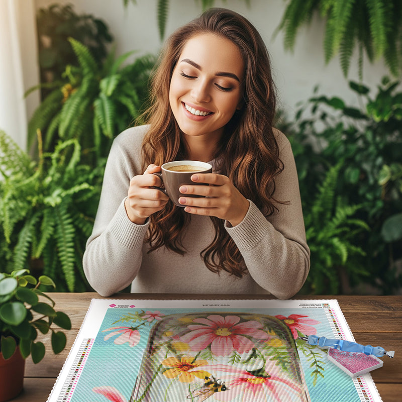 Frau hält Cafe in der Hand während sie vor ihrem Diamond Painting Kunstwerk sitzt