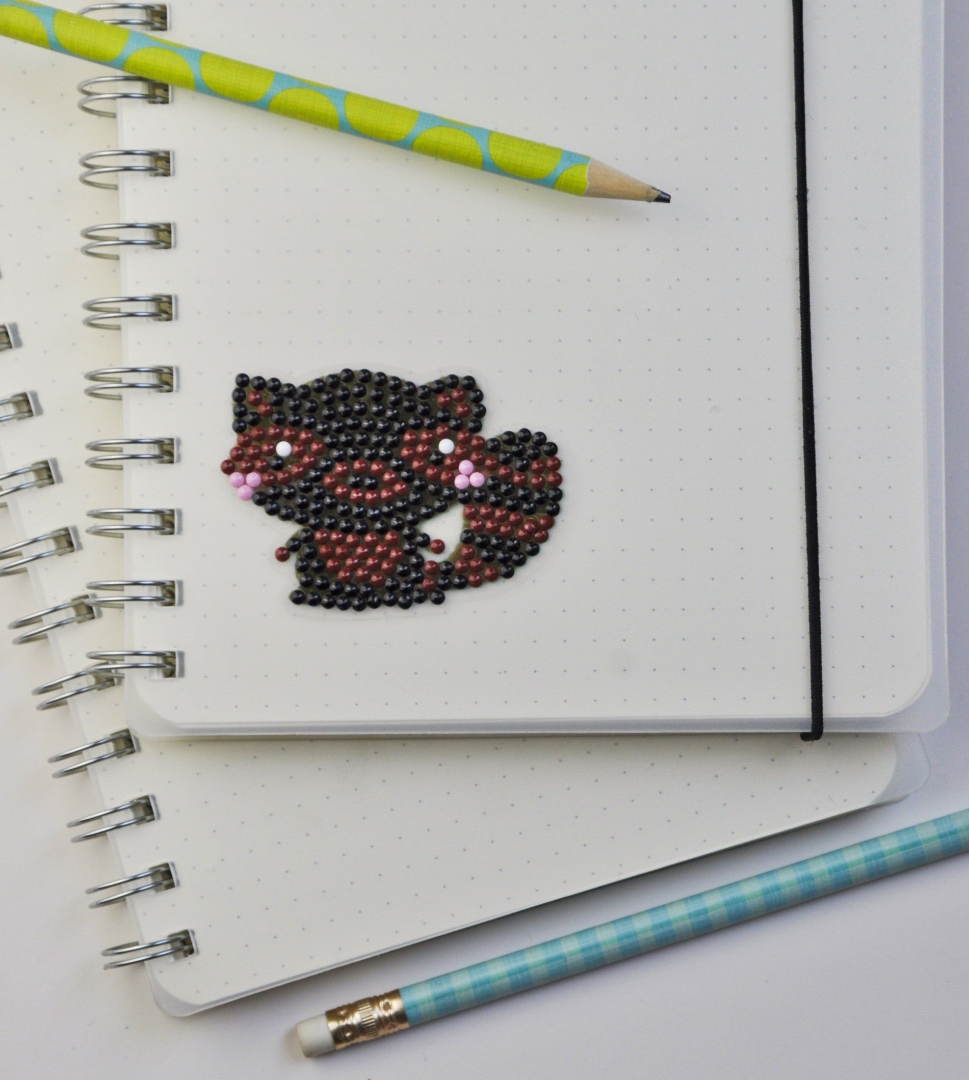 Diamond Painting Sticker mit niedlichem Waschbär-Motiv als persönliche Dekoration auf einem Notizbuch