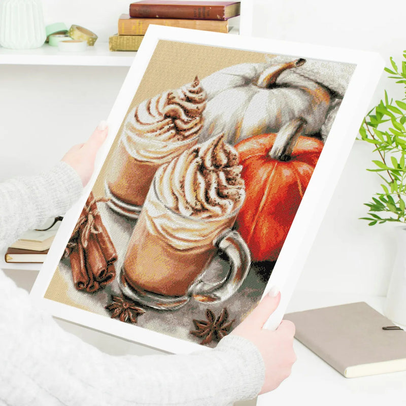 Diamond Painting fertig gerahmt mit herbstlichem Kaffee-Motiv und Zimt – wird in den Händen gehalten