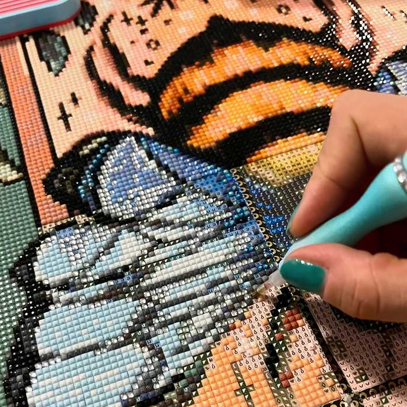 Diamond Painting Leinwand mit Bienenmotiv, glitzernden Steinchen und Hand mit Stift beim Painten